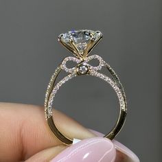 a close up of a person's hand holding an engagement ring