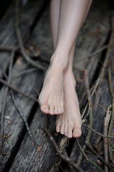 black and white photograph of bare feet on wooden floor with vines growing around the foot