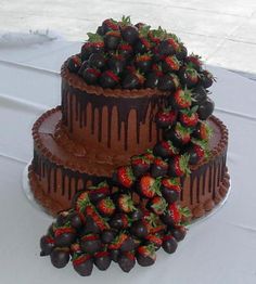 two tiered chocolate cake with strawberries and chocolate icing on the top layer