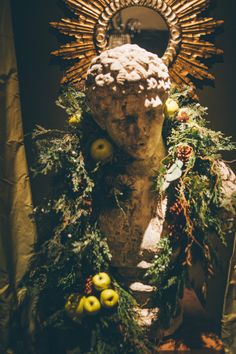 a statue with wreaths around it in front of a cross and mirror on the wall