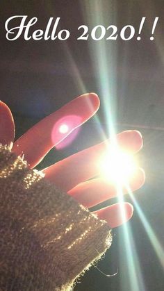 a person's hand holding a cell phone with the sun shining in the background