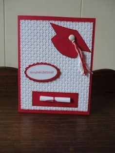 a red and white card with a graduation cap on it's side, attached to a wooden table