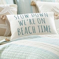 a pillow that says slow down we're on beach time sitting on a bed