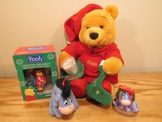 a winnie the pooh stuffed animal sitting next to two toys on a table with a box