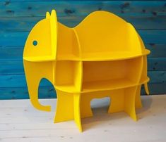 a yellow elephant shaped shelf sitting on top of a wooden floor next to a blue wall