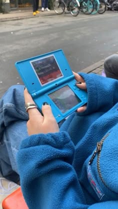 a person sitting on a bench with a blue tablet in their lap and holding the screen