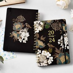 two notebooks sitting next to each other with flowers on them