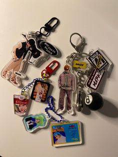 a collection of various key chains and magnets on a white surface, with one person standing in the middle