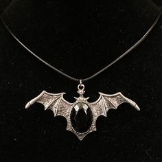 Please read descriptions thoroughly for sizes and materials. A special jewelry adhesive is use to attach pieces to bails where noted.  This is a large eye catching silver metal pendant featuring a silver bat type shape, with its wings spread, and a large black resin cabochon. It is hung from a black faux leather woven waxed cord that is 19 1/2" long, with silver chain and a silver lobster claw clasp. * Also available on a 18" 20"or 30" silver stainless steel snake chain.  Make sure to check out my shop for more hair pins, jewelry, accessories, and all sorts of fun stuff! Bat Necklace, Goth Necklace, Gothic Necklace, Wing Necklace, Bat Wing, Silver Black Bat, Vampire Jewelry, Bat Jewelry, Vampire Necklace Jewelry Vampire, Vampire Necklace, Vampire Jewelry, Bat Jewelry, Bat Necklace, Resin Cabochon, Goth Necklace, Necklace Gothic, Goth Jewelry