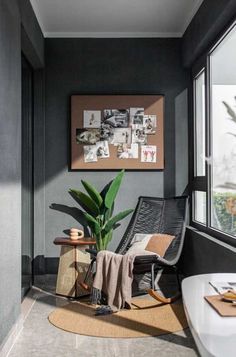 a room with a chair, potted plant and pictures on the wall