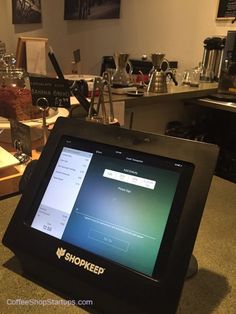 a tablet sitting on top of a counter next to a coffee pot filled with liquid