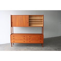 a wooden shelf with drawers and shelves on the top, in front of a white wall