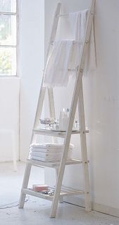 a white ladder leaning against a wall with towels on it