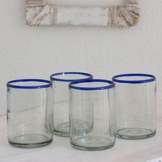 four blue rimmed glass cups sitting on a table in front of a white wall