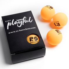 three ping pong balls sitting on top of a box next to it's packaging