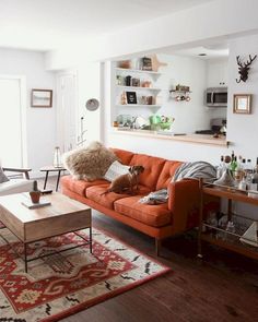 a living room filled with furniture and a dog on top of a red couch next to a coffee table