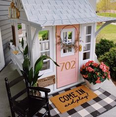 a small dollhouse with a rocking chair and potted plants on the front porch