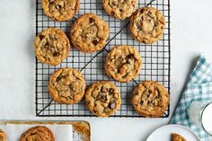 chocolate chip cookies cooling on a wire rack next to a glass of milk and two plates