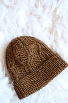 a brown knitted hat laying on top of white fur