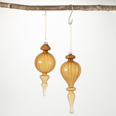 two wooden ornaments hanging from a branch on a white background, one is shaped like a balloon and the other is shaped like a bird