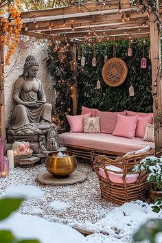 an outdoor living area with a buddha statue in the center and pink cushions on the couches