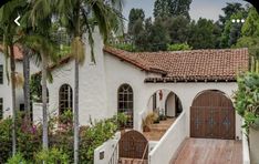 a white house with brown doors and palm trees