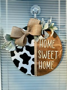 a door hanger that says home sweet home with a cow print design on it