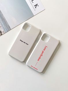 two cell phones sitting next to each other on top of a white table with a magazine in the background