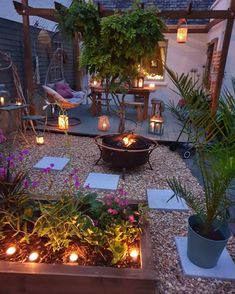 an outdoor patio with candles lit up in the center and potted plants on the other side