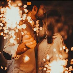 a man and woman standing next to each other holding sparklers