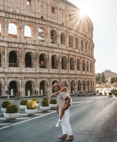 a man and woman standing in front of the colossion with sun shining on them