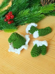 three crocheted christmas ornaments sitting on top of a wooden table next to pine branches