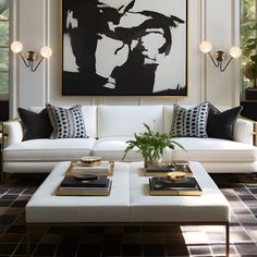 a living room with white couches and black and white artwork above the coffee table