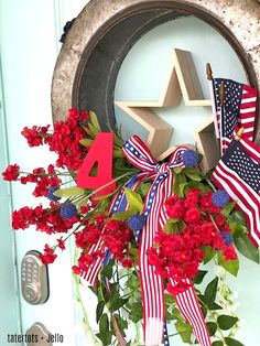 a patriotic wreath with red, white and blue flowers in front of a star shaped door hanger