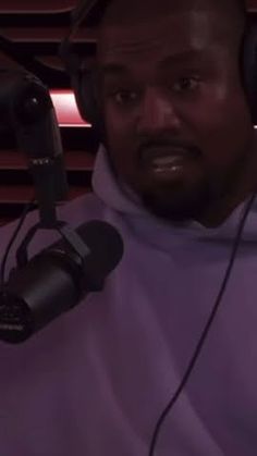 a man with headphones on is in front of a microphone and wearing a purple hoodie