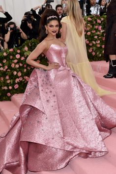 a woman in a pink gown standing on stairs