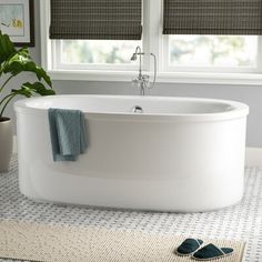 a white bath tub sitting next to a window with shades on the windowsills