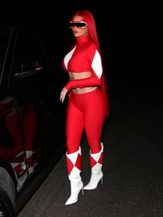 a woman in red and white outfit standing next to a car