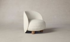 a white chair sitting on top of a floor next to a gray wall and wooden legs