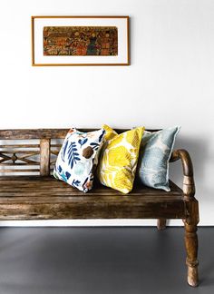 a wooden bench with four pillows on it