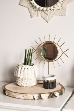 a mirror and some plants on a white table with a wooden slice in the foreground