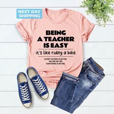 Cute Teacher Shirt, Being A Teacher Is Easy Back To School Like Riding A Bike, School Shirt, Funny Teacher Shirt, Unique Gift, Teacher Gift Hi! Welcome to the LaTeeApparel!  It's great to see you here! Our shirts are clean, high quality and soft. It is prepared quickly by our store! Enjoy your shopping! It is a pleasure for us to help you with your questions and you can reach us at any time. F I T  ∙ S I Z I N G  -->Women's sizes are narrower than the waist -->Sleeves are rolled up in some produ Short Sleeve Graphic Print Cycling Tops, Graphic Print Short Sleeve Cycling Top, Graphic Print Short Sleeve Tops For Cycling, Casual Cotton T-shirt For Cycling, Male Teacher Shirts, Preschool Teacher Shirts, Male Teacher, Being A Teacher, Riding A Bike