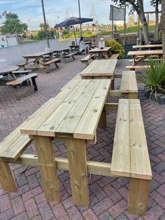 several picnic tables and benches are set up on the brick walkway in front of an outdoor seating area