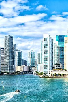 a boat is traveling through the water in front of some tall buildings and skyscrapers