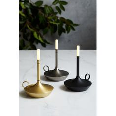 three black and gold utensils sitting on a table next to a potted plant