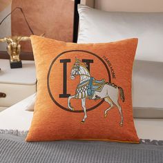 an orange pillow with the letter t on it and a white horse in a circle