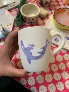 a hand holding a coffee cup with an image of a whale on it