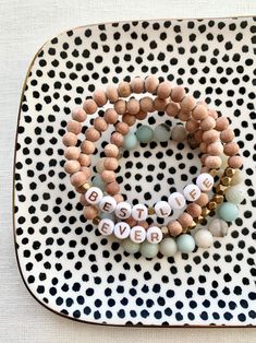 two beaded bracelets sitting on top of a white and black polka dot plate