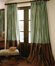 a living room scene with focus on the door and window curtained drapes