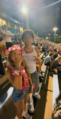 two people standing next to each other in front of an audience at a baseball game